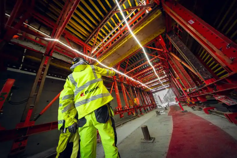 RAWA teknikkere står i stilladsgang på stort byggeprojekt og peger
